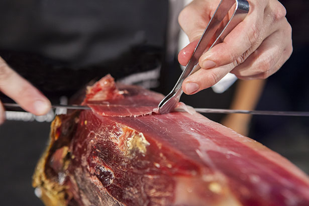 Picture of Someone Finely Slicing a Leg of Prosciutto.