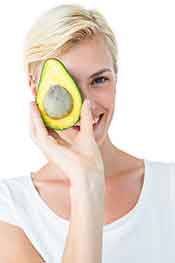 Young Woman Holding a Half Avocado Near Her Face.